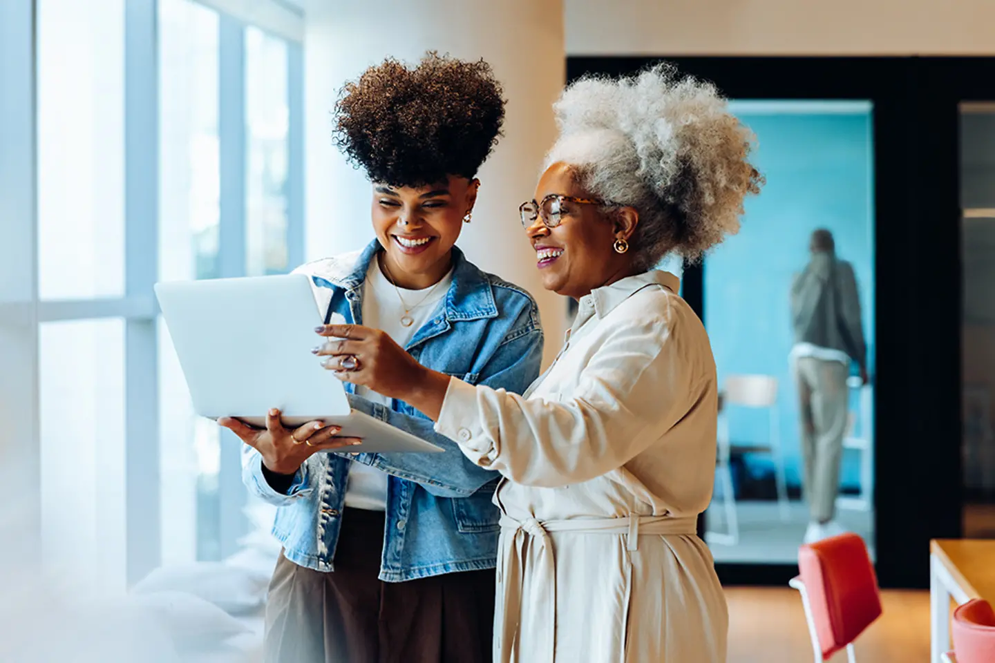 Two female colleagues using AI in office environment