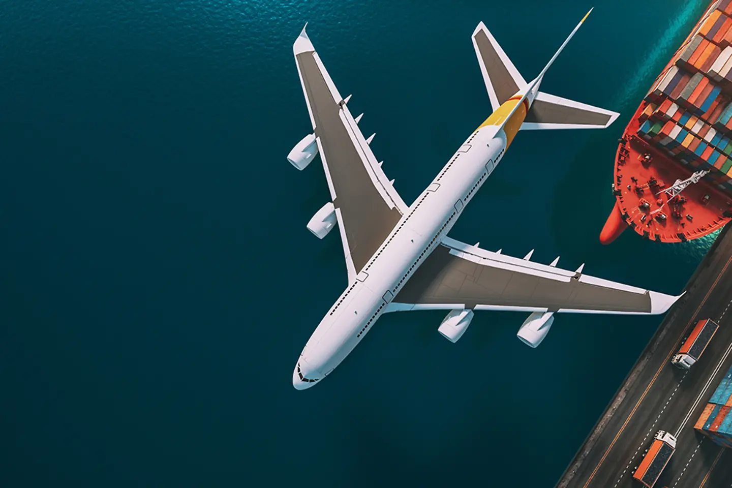 Flugzeug, Frachtschiff, und LKWs in einem Hafen.