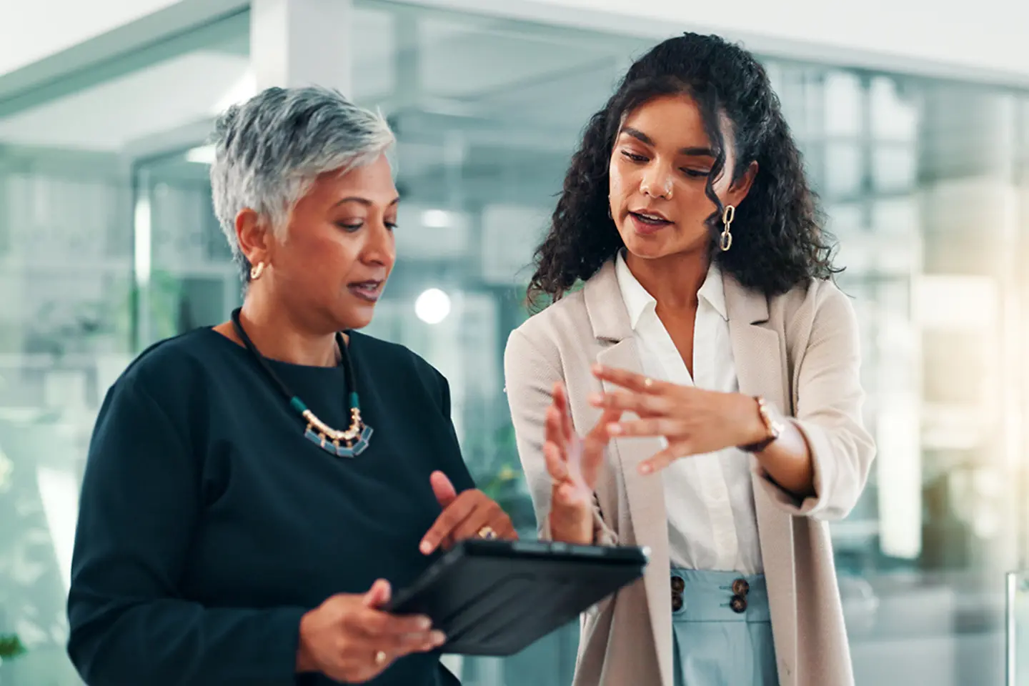Female consultant discussing data with female manager on tablet
