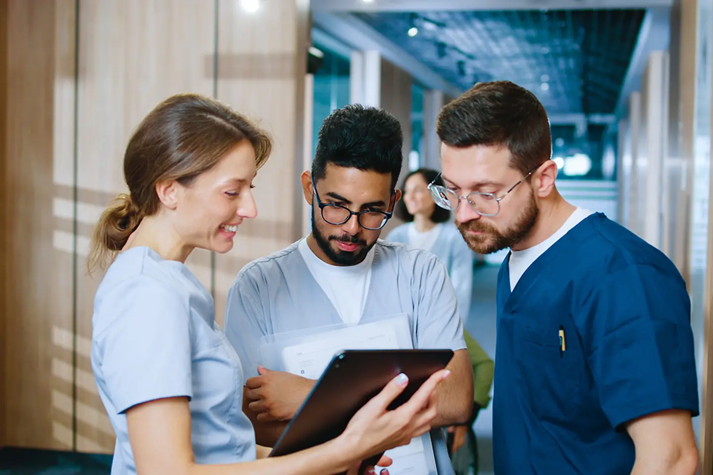 Young medical professionals of diverse backgrounds exchanging ideas during a break in a modern hospital corridor