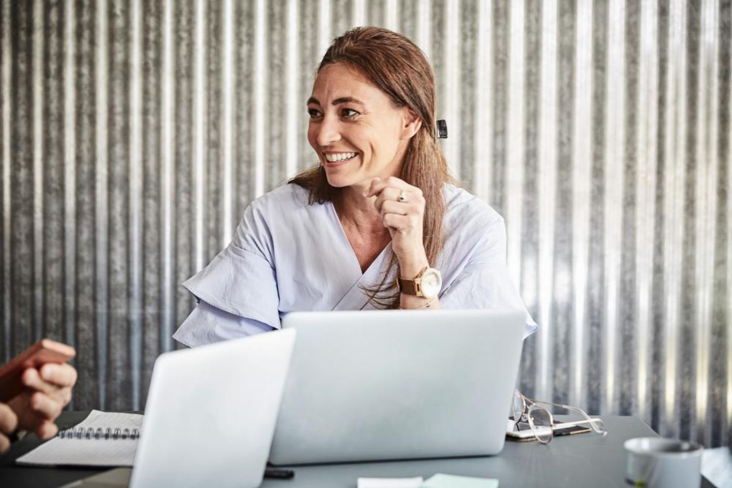 Happy woman behind her laptop sitting together with others in a conference room