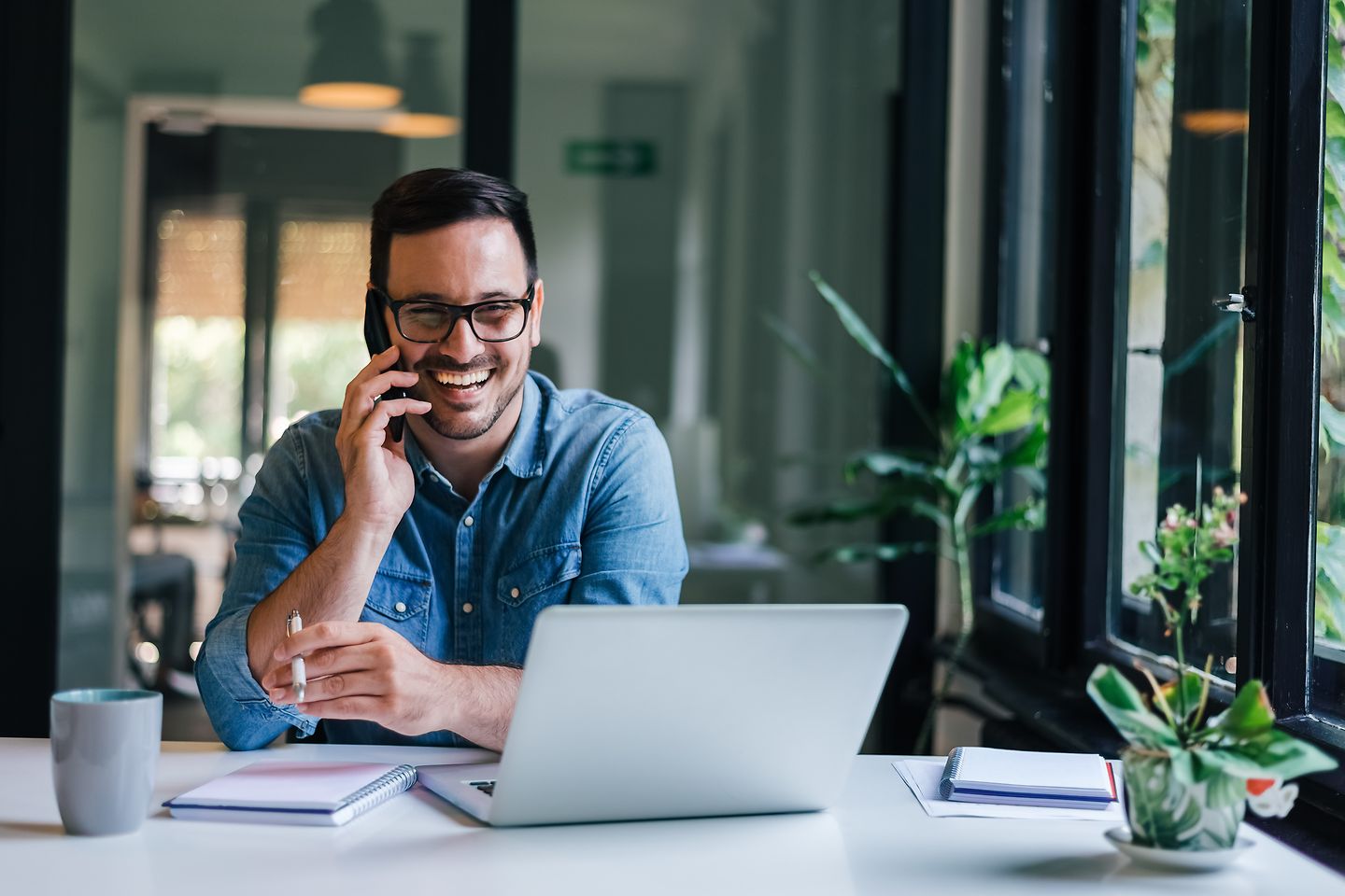 Mann telefoniert am Arbeitsplatz und lacht