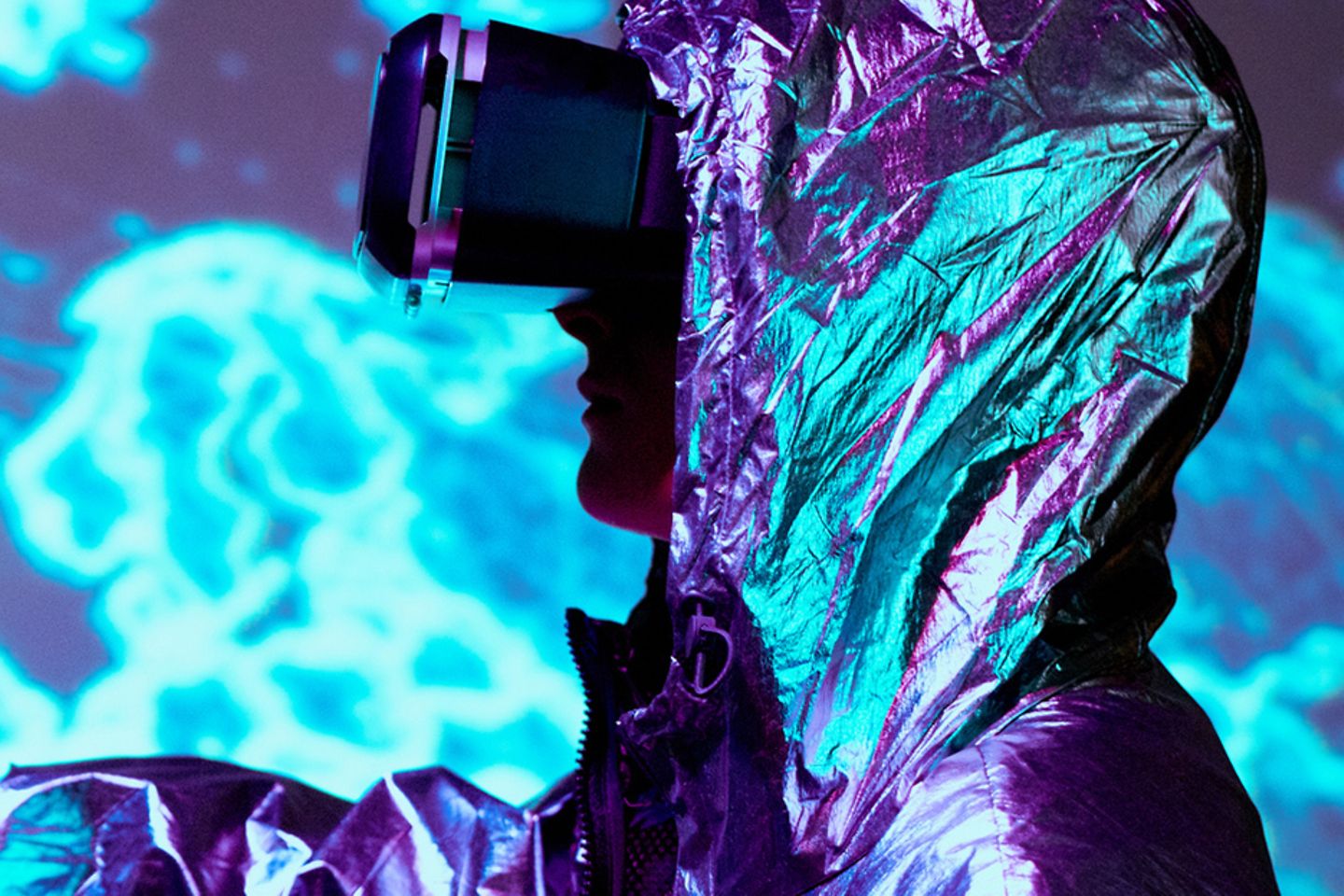 Man in silver suit with futuristic VR-glasses points to a glowing map of the world.