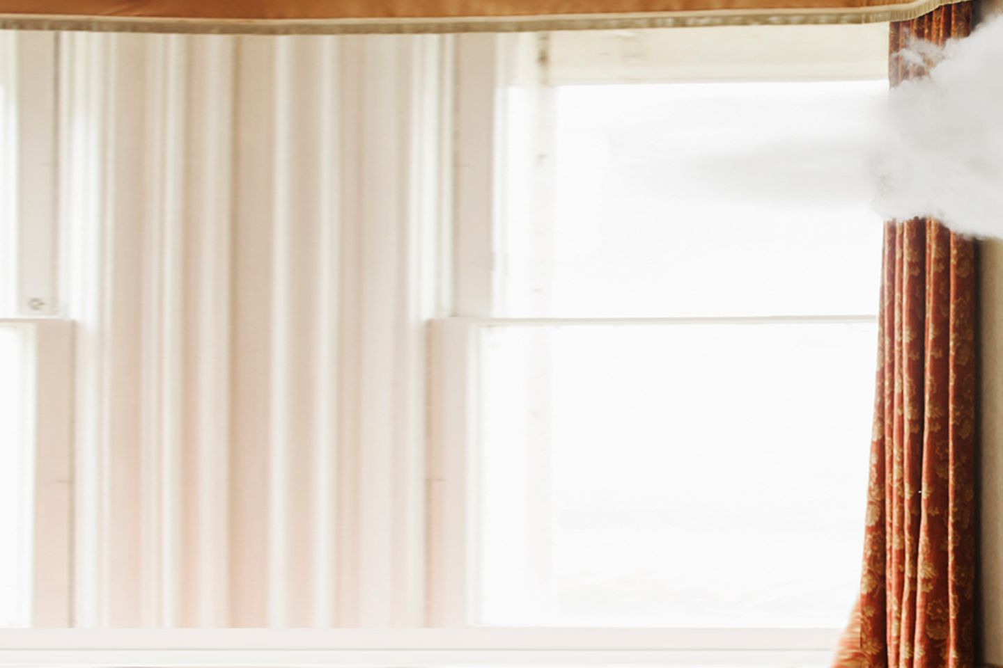 Woman stands in living room and looks up to a small white cloud above her head.