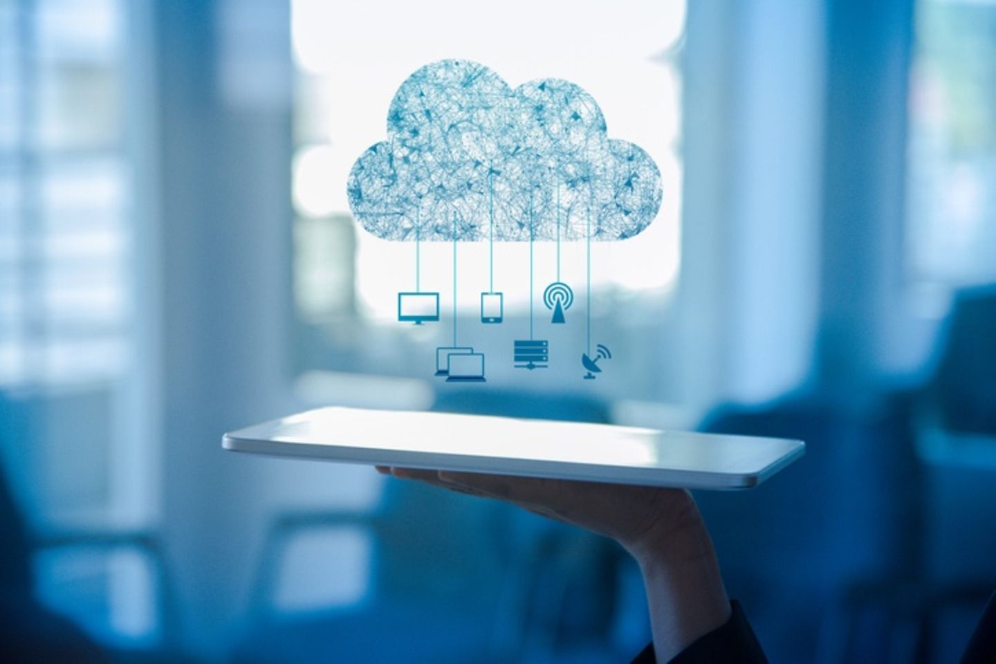A tablet lies on one hand, above it is a drawing of a cloud and icons.