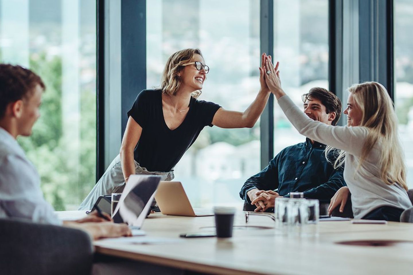 Two businesswomen high five each other in a meeting