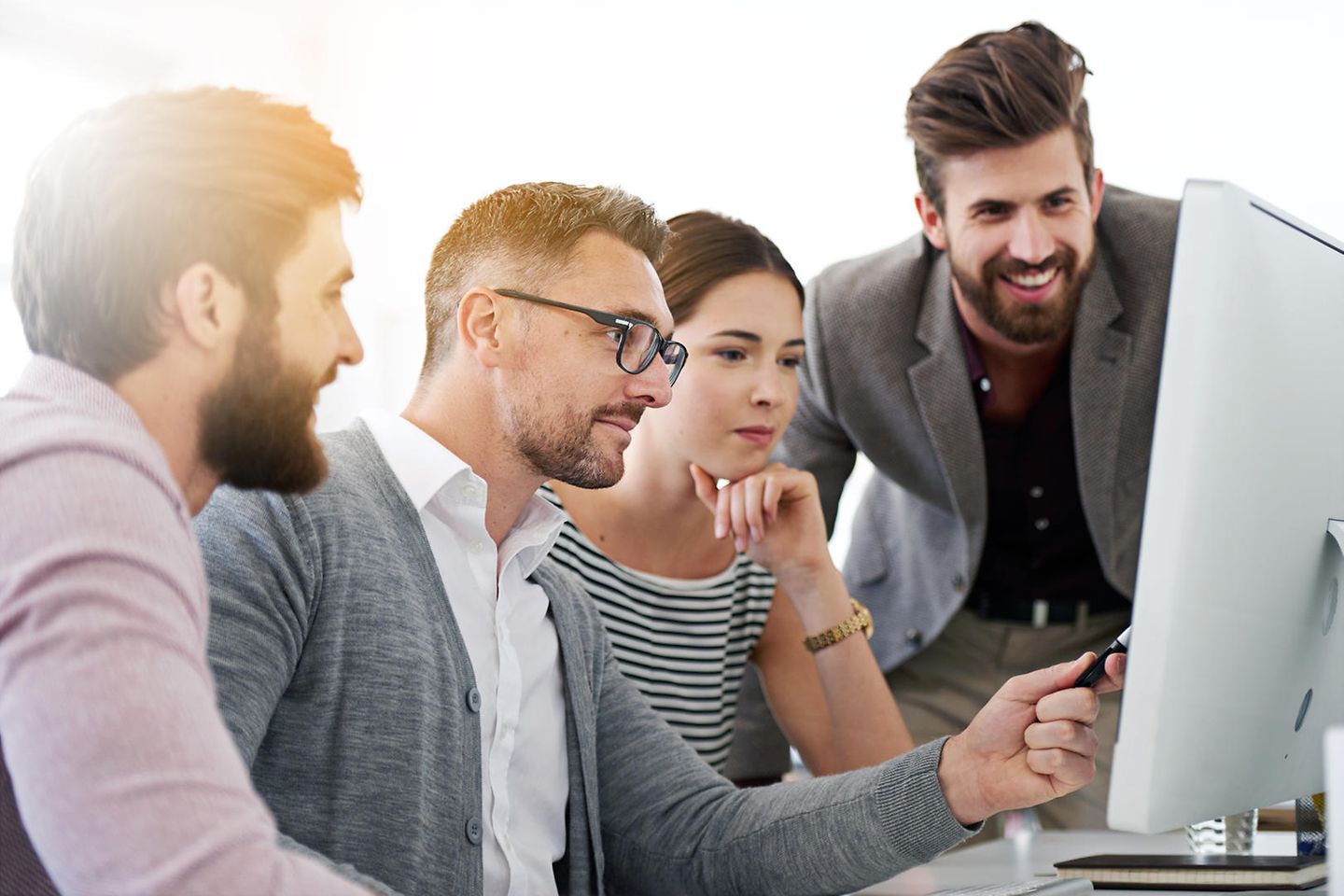 Young employees sit together in front of a screen