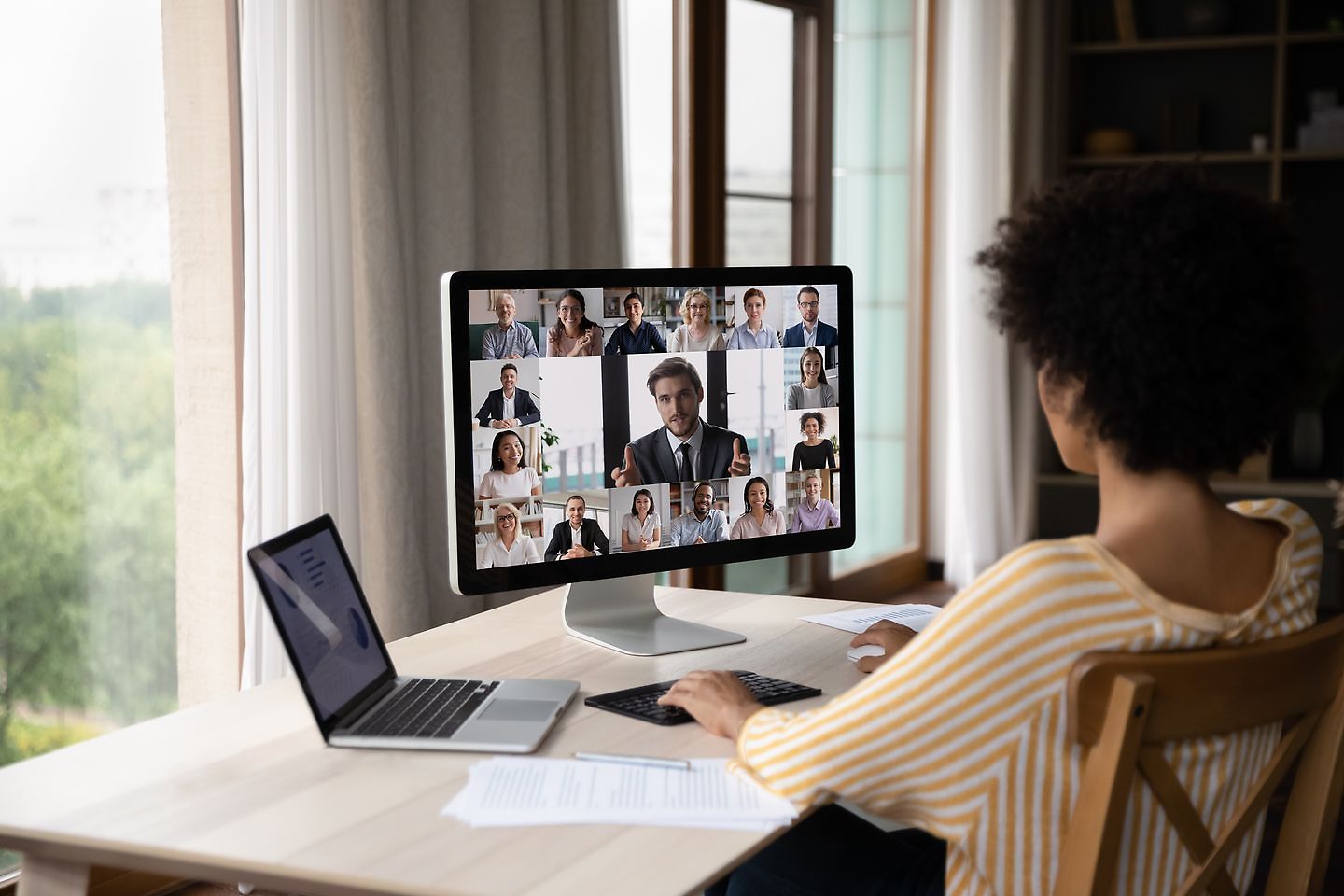 A woman sits at her desk in her home office and works on her laptop