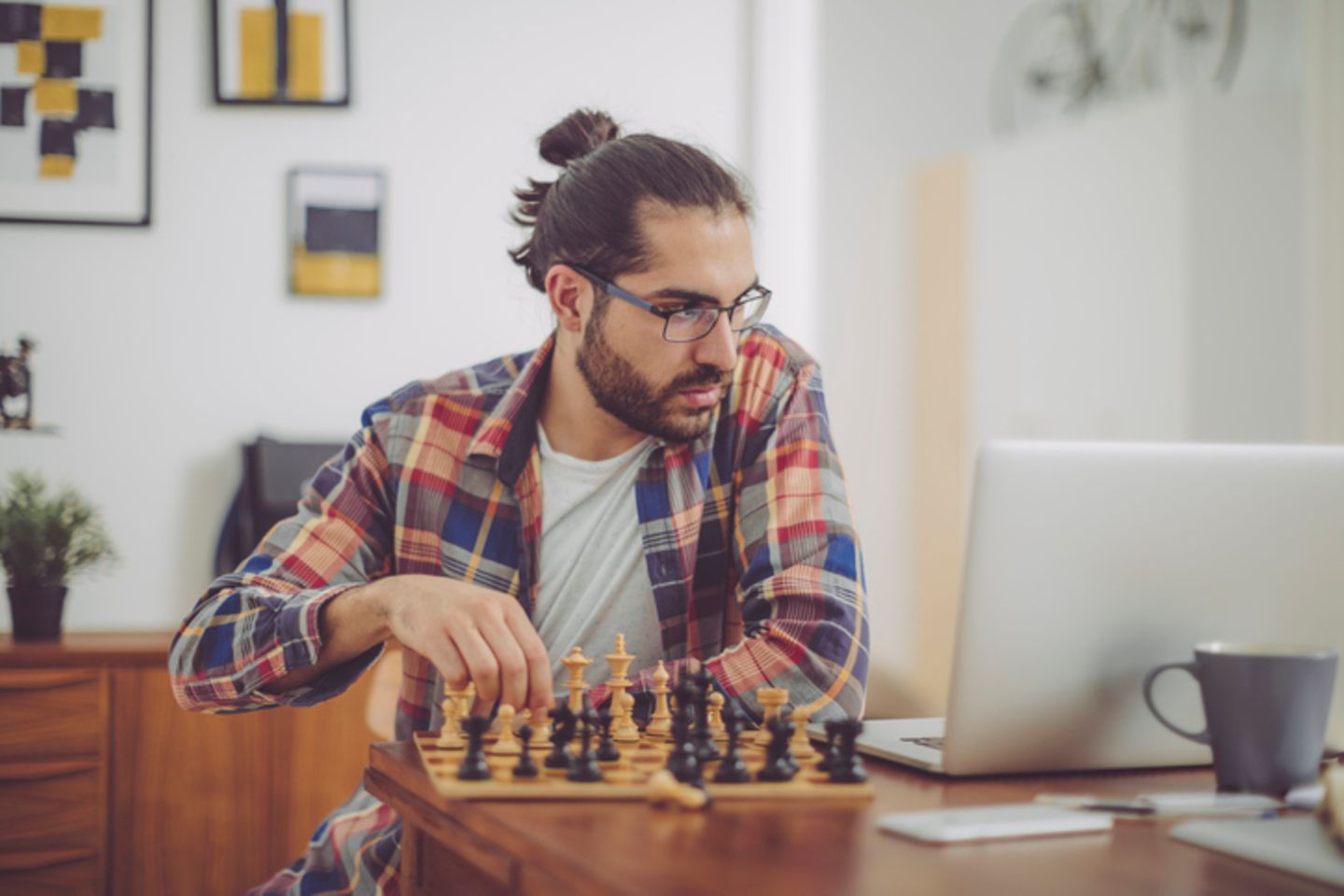 Mann spielt Schach und schaut auf den Laptop
