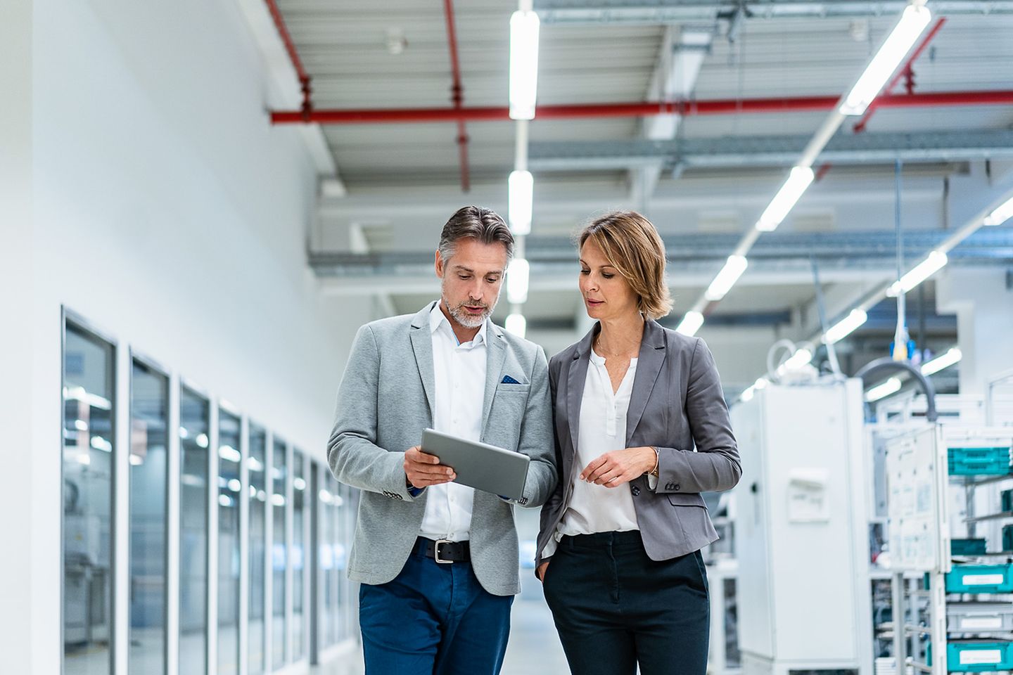 Businessman shows businesswoman something on a tablet screen in a production hall