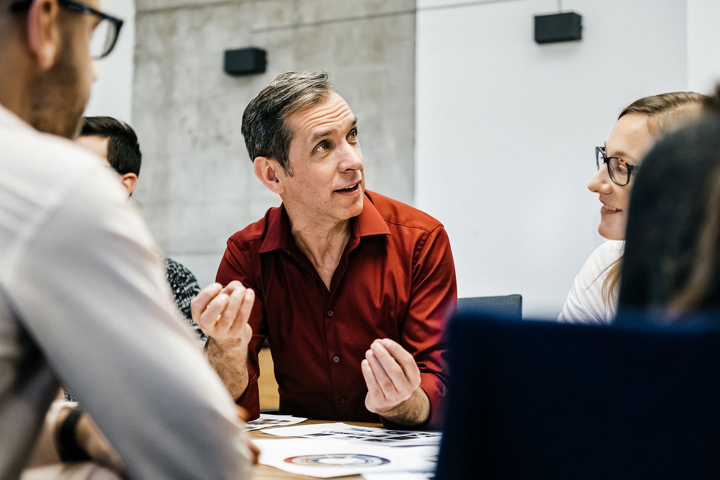 A man discussing in a round of people, gesticulating with his hands