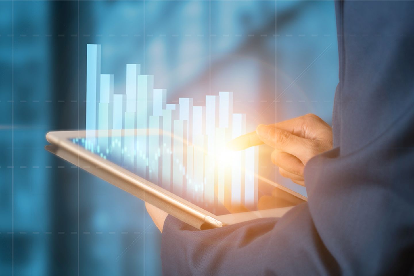 Ein Geschäftsmann tippt auf ein Tablet, aus dem Finanzdiagramme herauswachsen. 