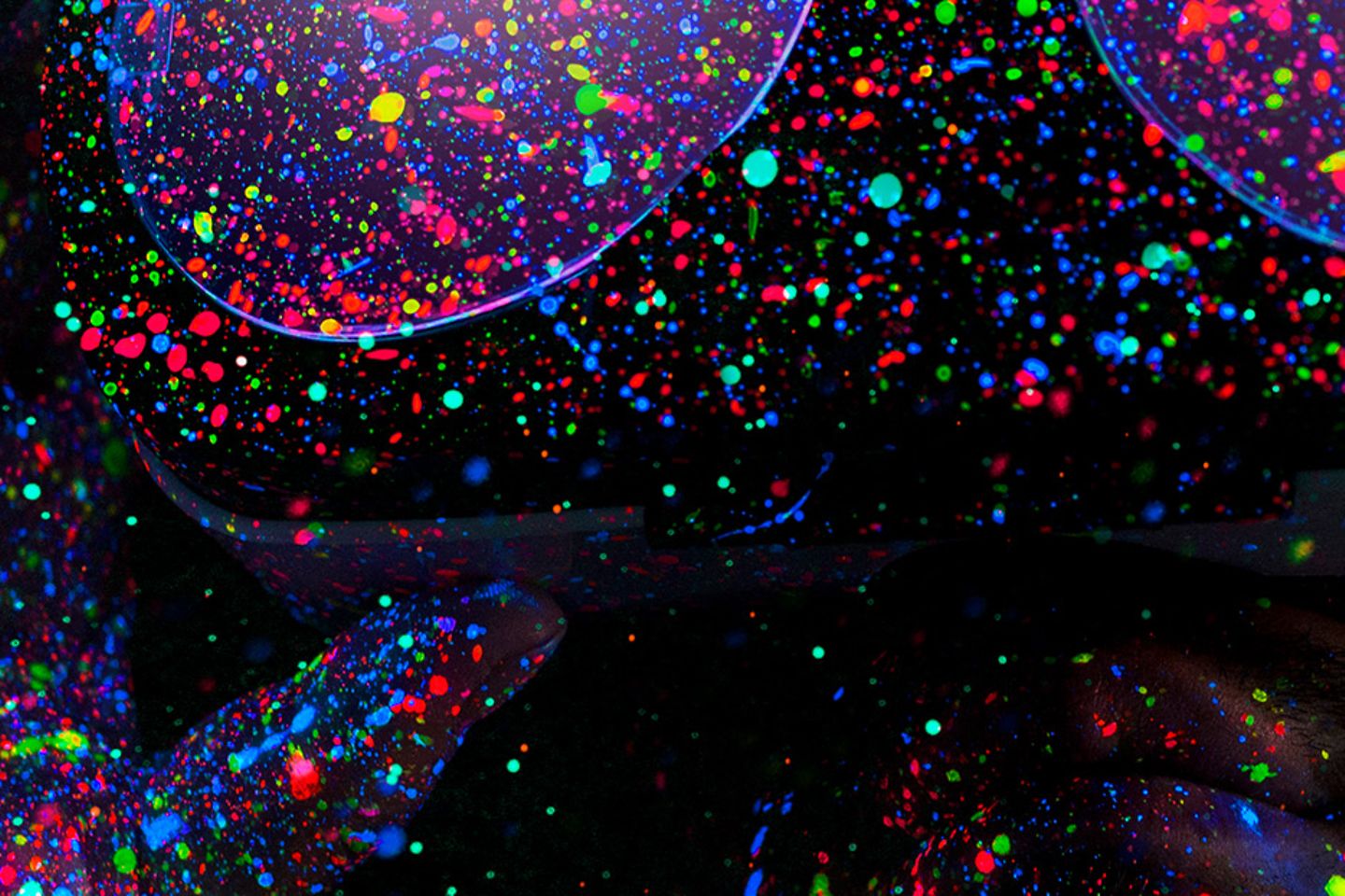 Man sees through VR-glasses; the background is dark and there are colourful neon speckles everywhere