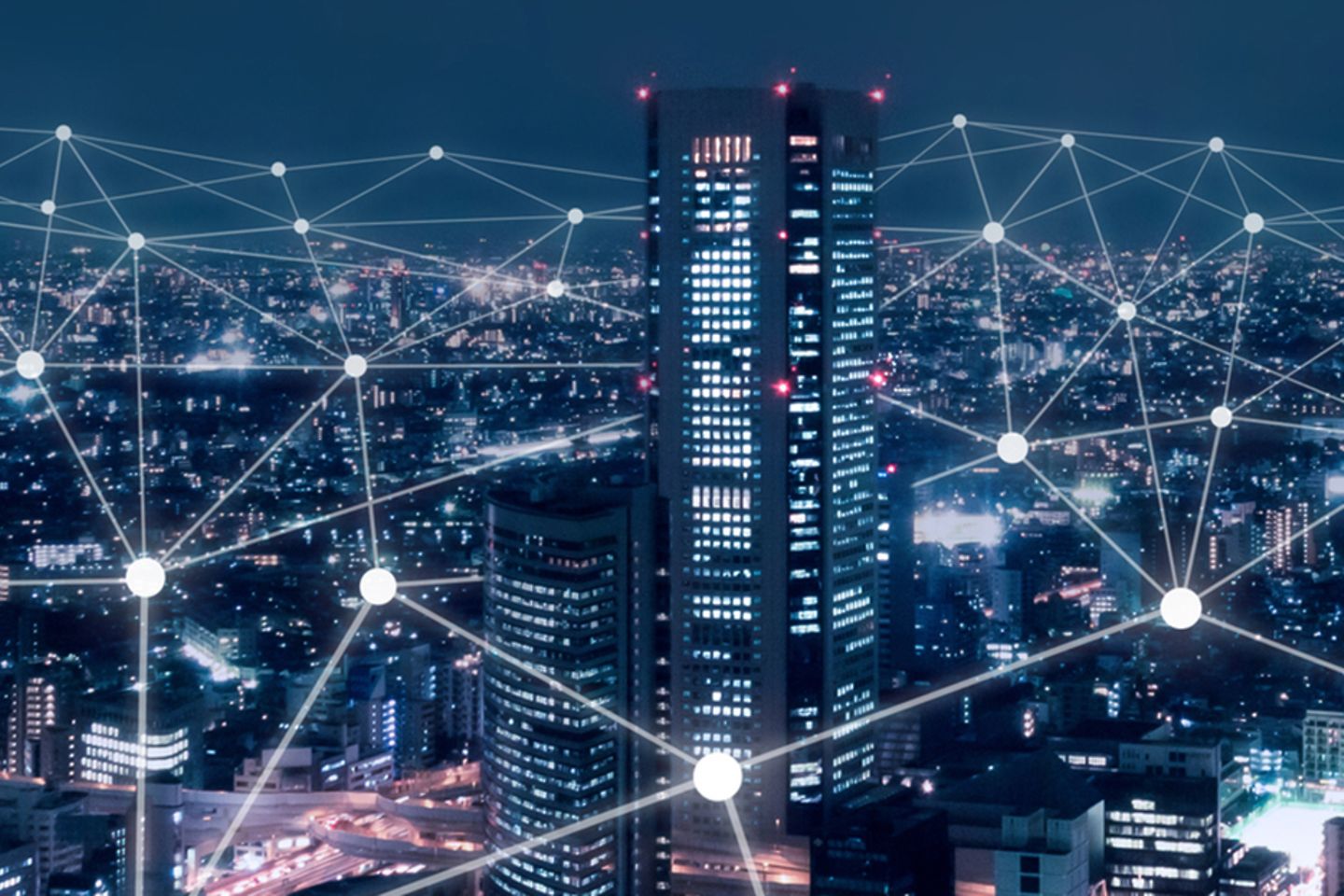 Skyline of a big city at night, bright points of light and lines can be seen in the sky.