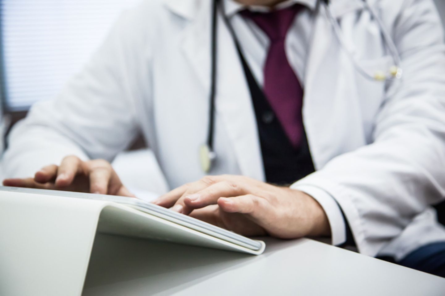 A doctor sits at a table and uses a tablet.