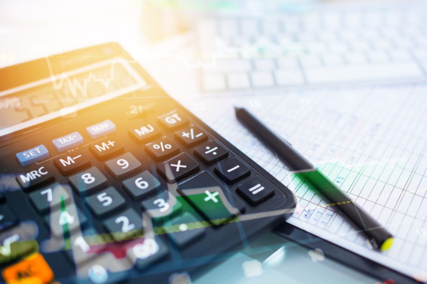 A pen on paper and a keyboard next to a pocket calculator.