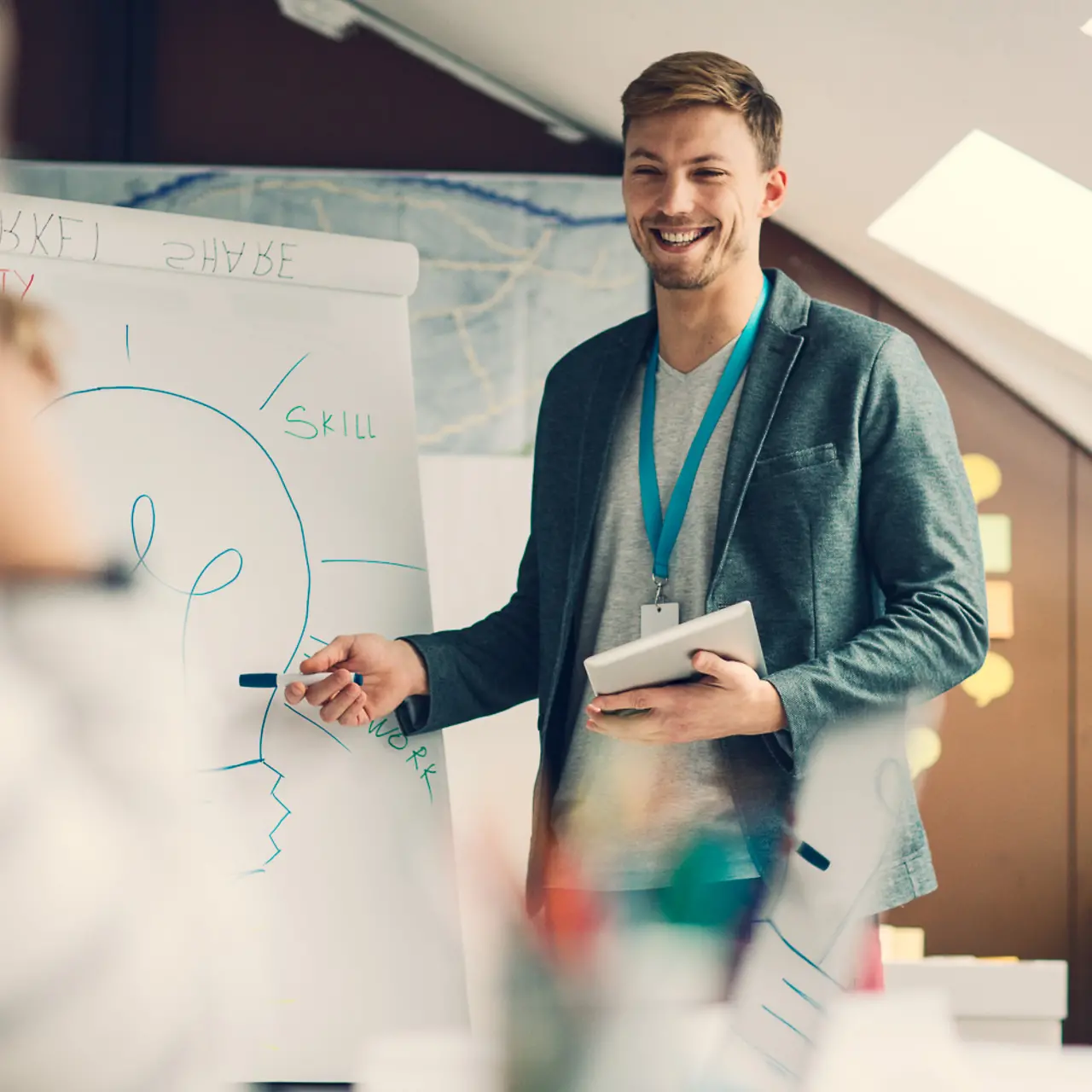 Young man presents his colleagues an idea on a whiteboard