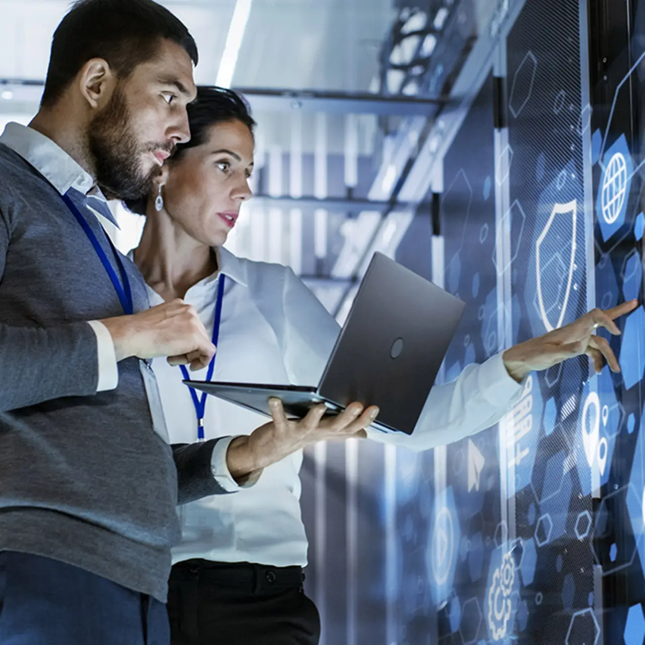 Una mujer y un hombre parados frente a una pared de pantalla y discutiendo temas de seguridad