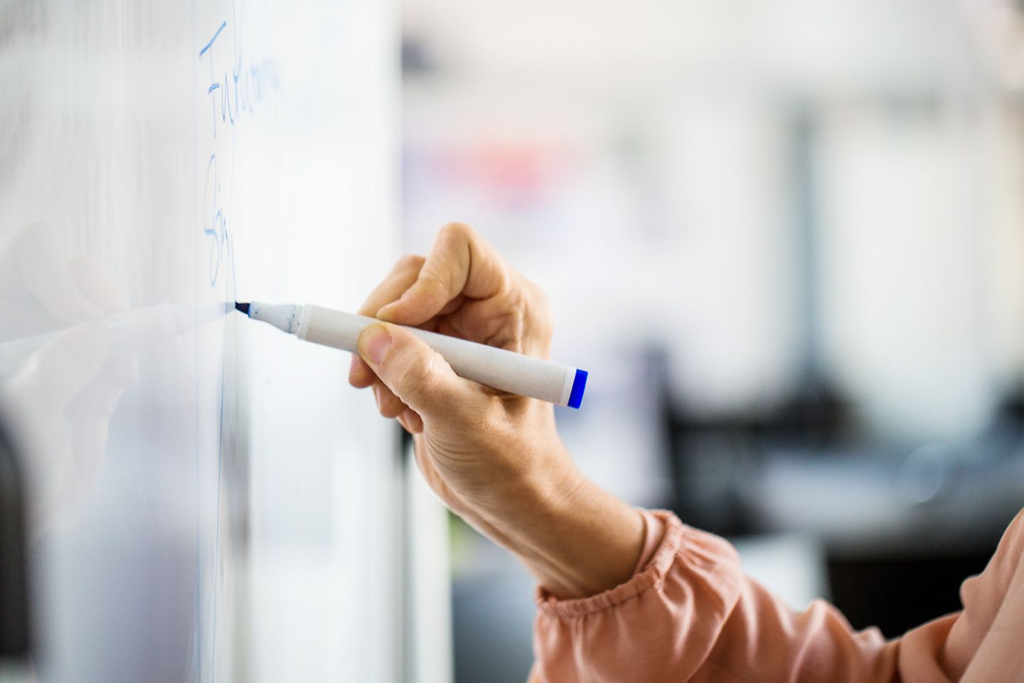 Vrouw schrijft met een blauwe stift op een whiteboard