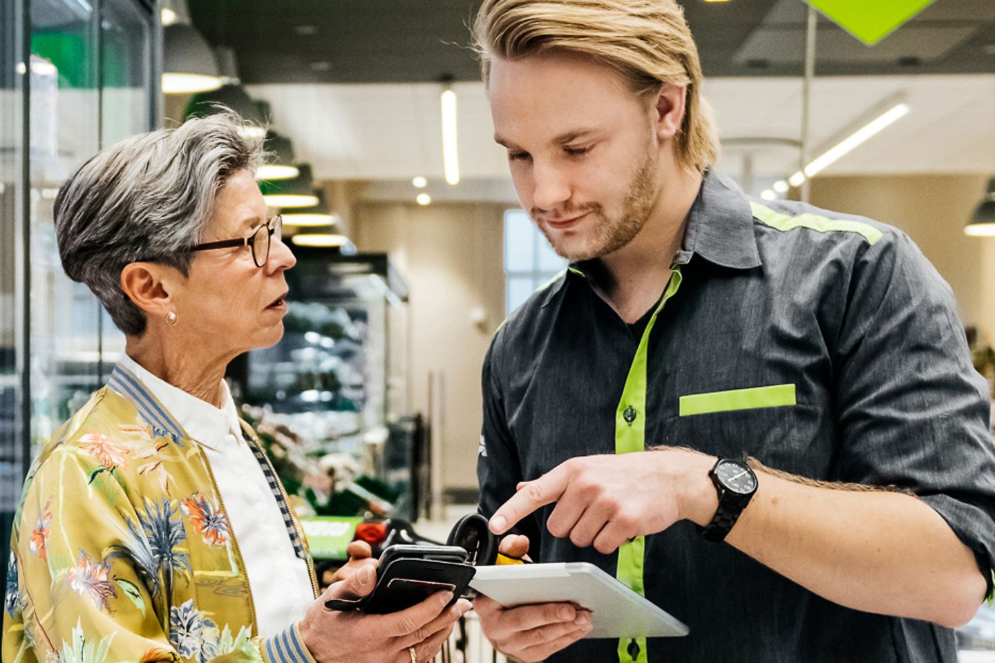 Jonge verkoper en winkelmanager staan voor het koelschap en vergelijken gegevens op een tablet