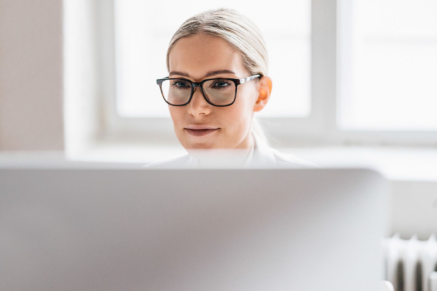 Jonge vrouw met donkere bril zit achter een computerscherm
