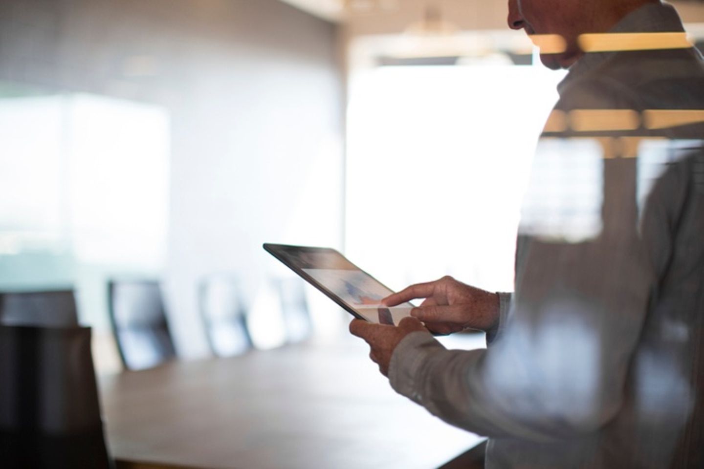 Empty conference room with a standing man tapping a tablet