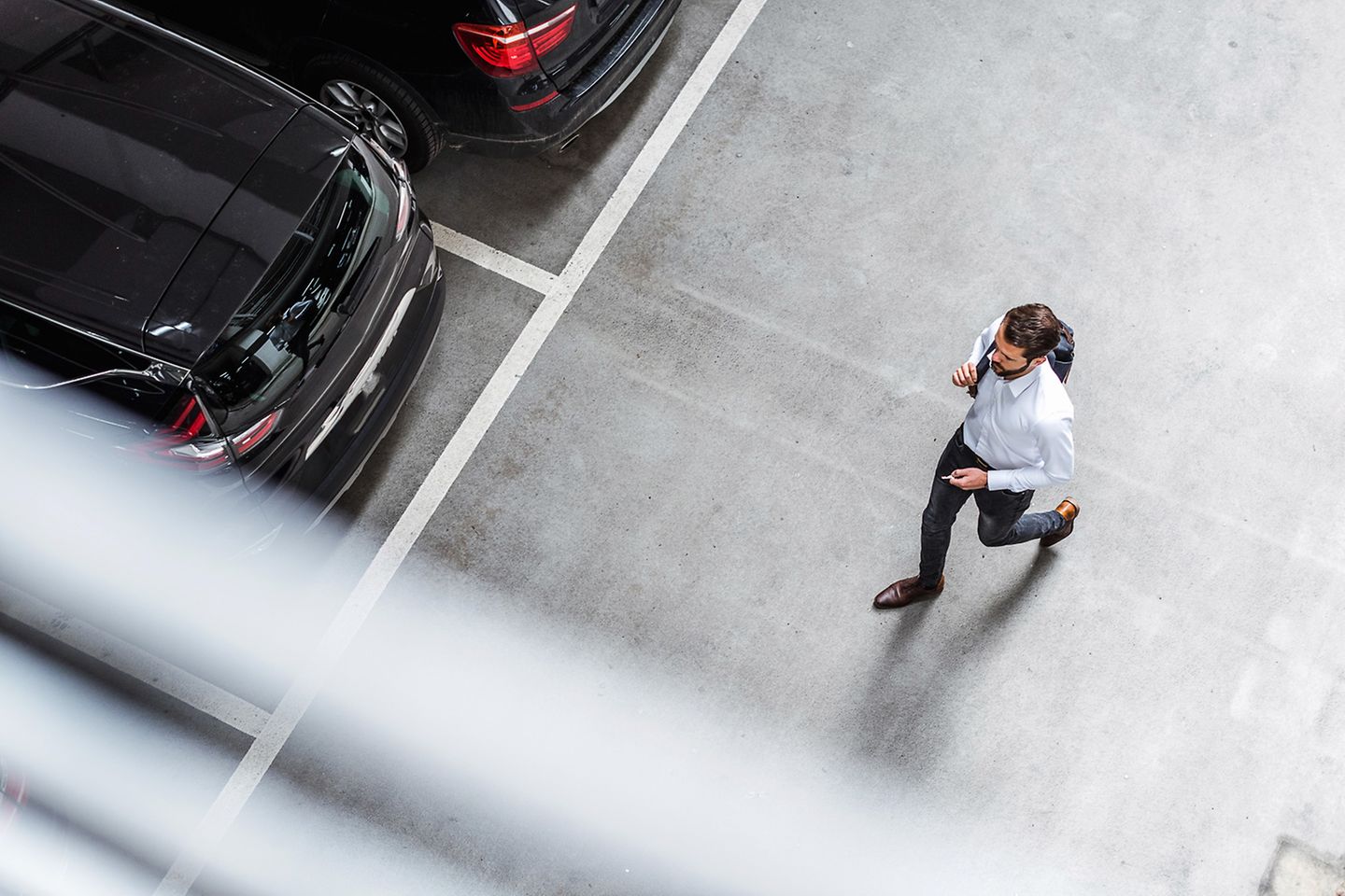 Een man loopt op een parkeerplaats naar een geparkeerde auto