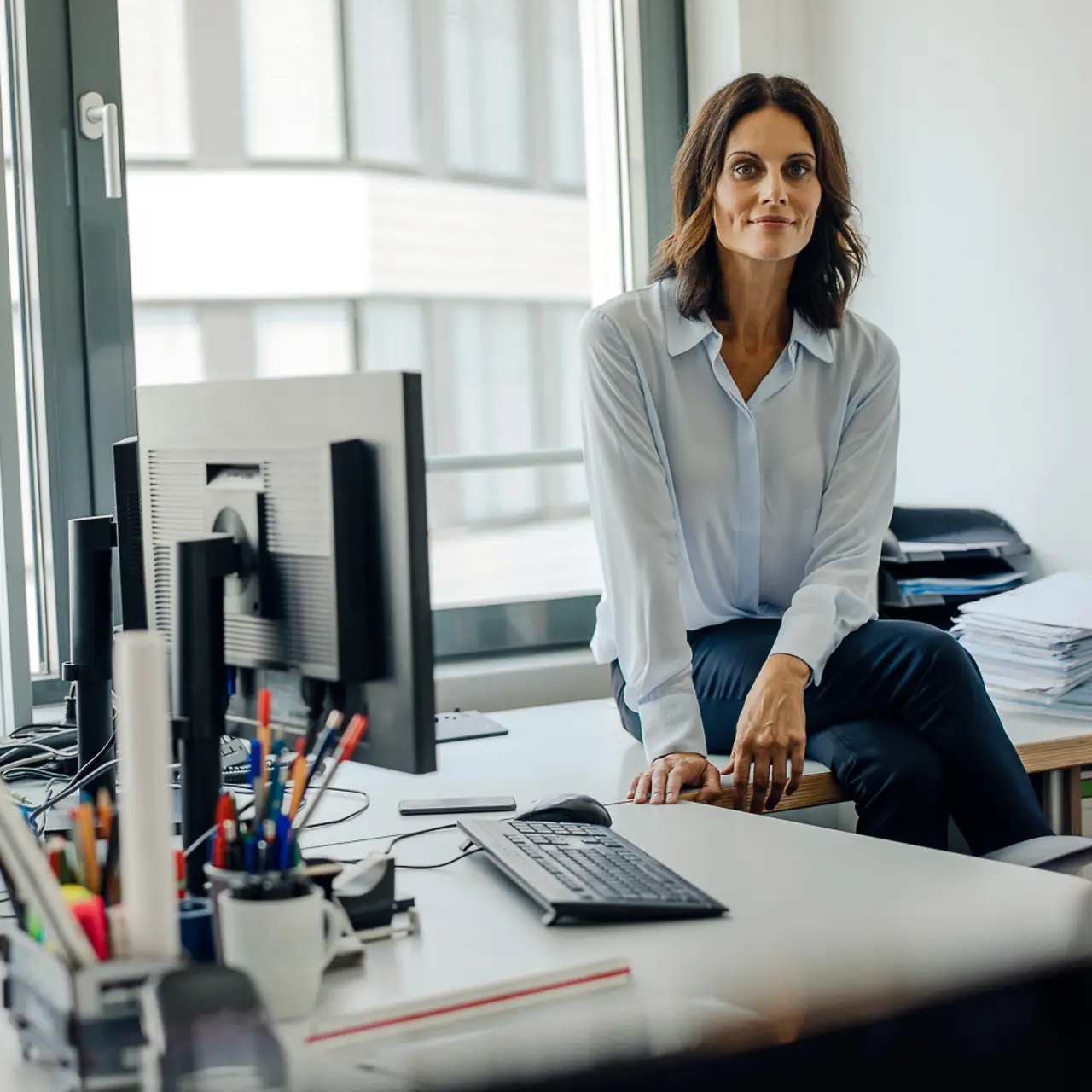 Mujer sentada sobre el escritorio en la oficina
