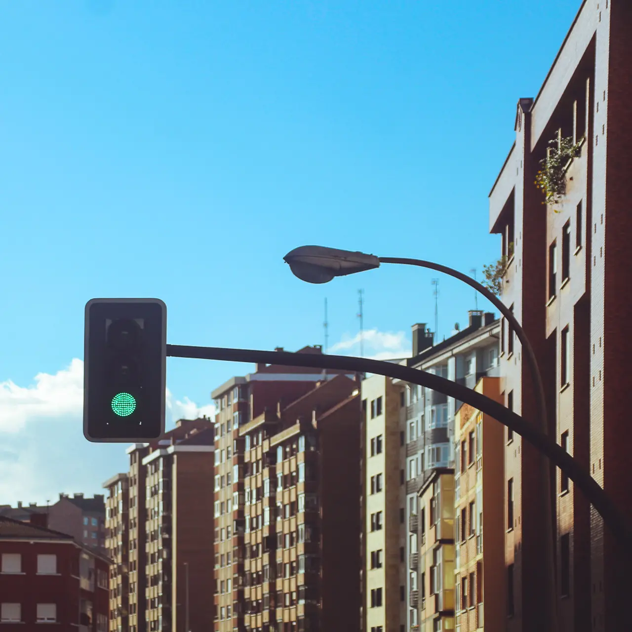 Vista de día de una calle con edificios altos de una gran ciudad, sin tráfico, con un semáforo en verde en el centro de la...