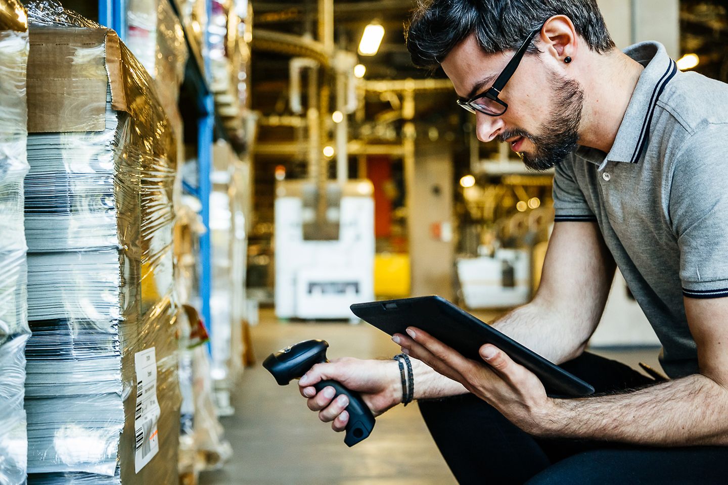 Empleado de fábrica escaneando mercancía y verificándola en una tablet