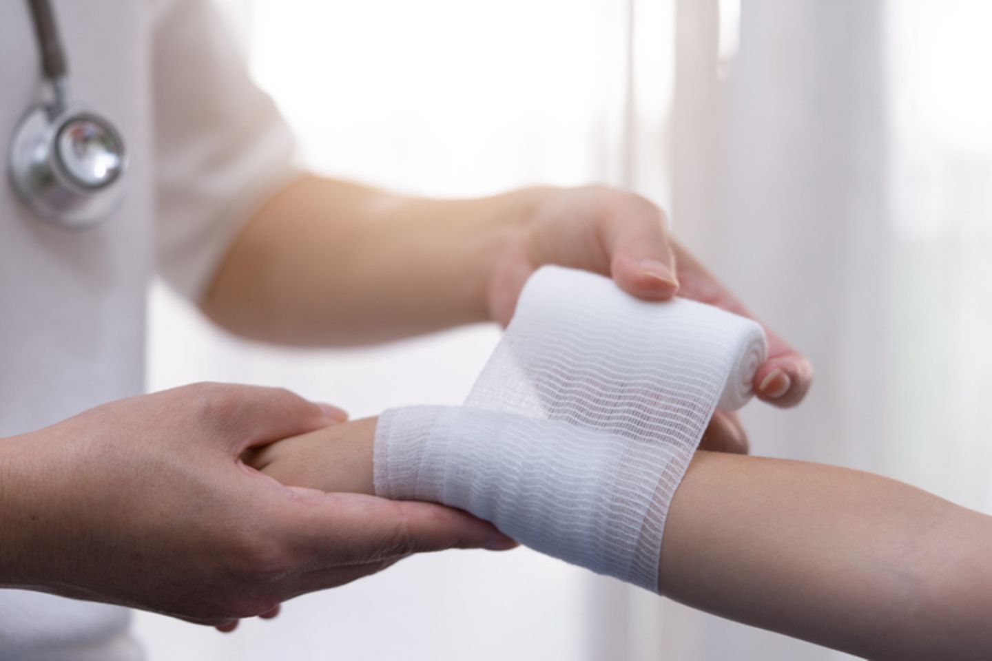 A nurse winds a gauze bandage around an arm
