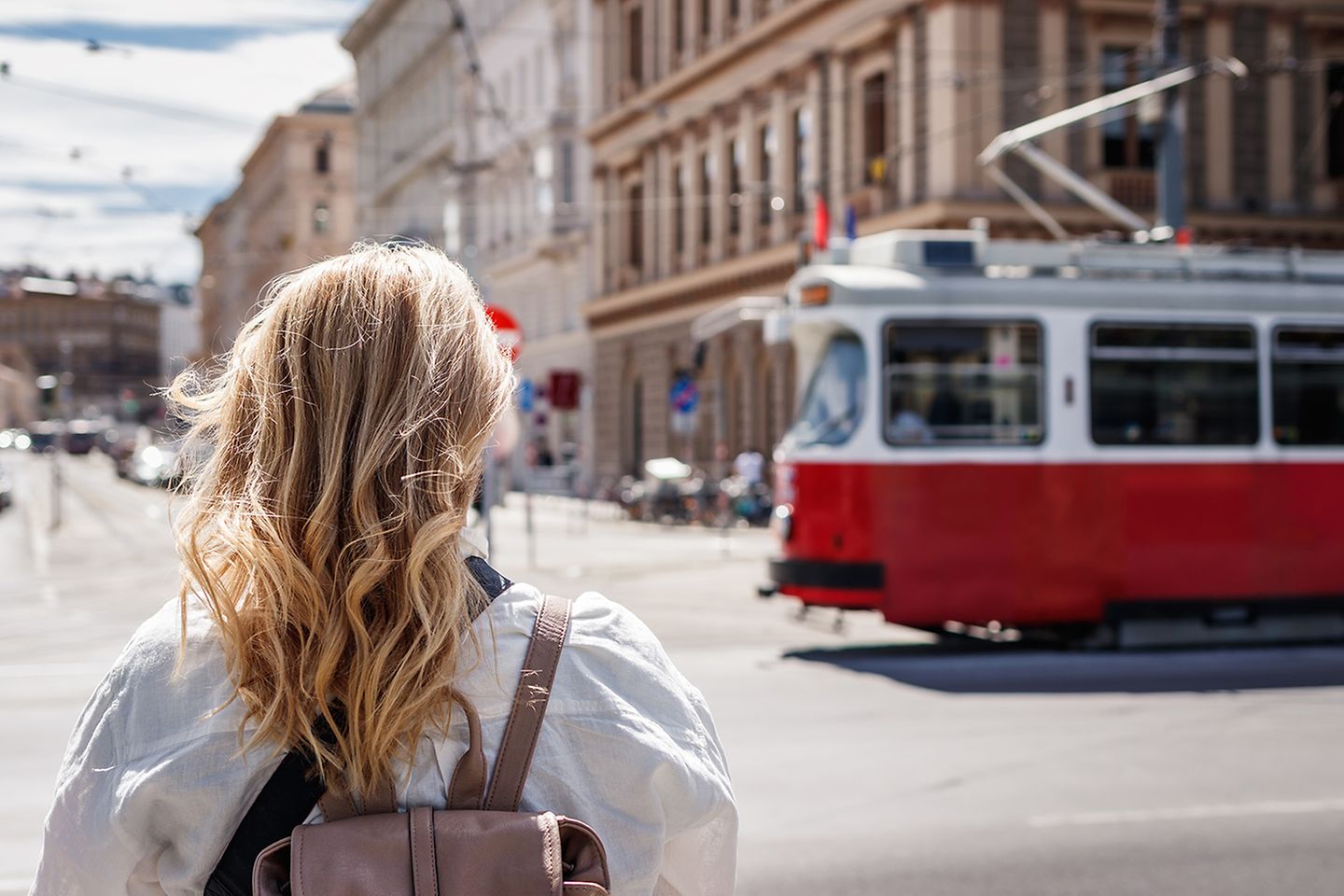 Frau von hinten mit Blick auf eine Straßenbahn