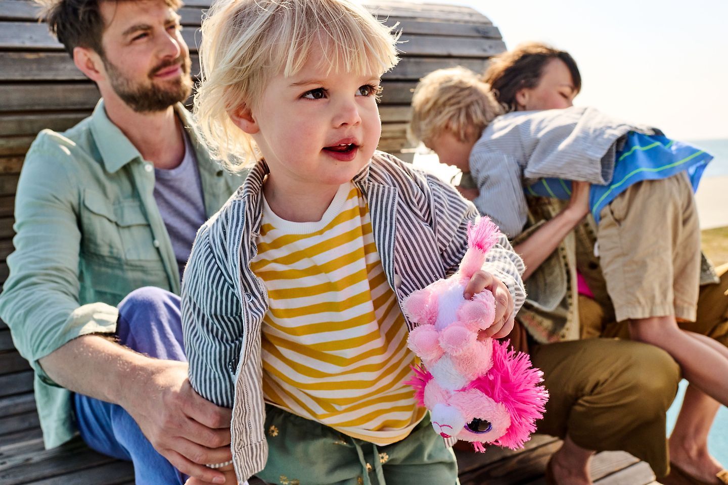 Familie sitz auf einer Holzbank am Strand