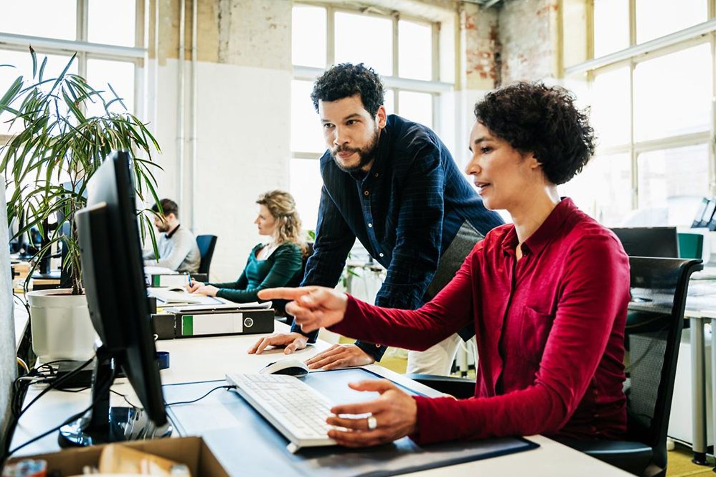 Business-Kollegen schauen gemeinsam auf den Computer und unterhalten sich