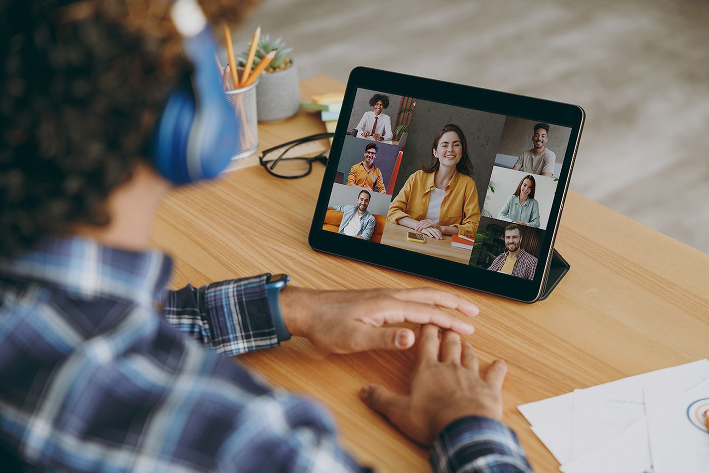 Person sitzt vor einem Tablet und hat eine Videokonferenz