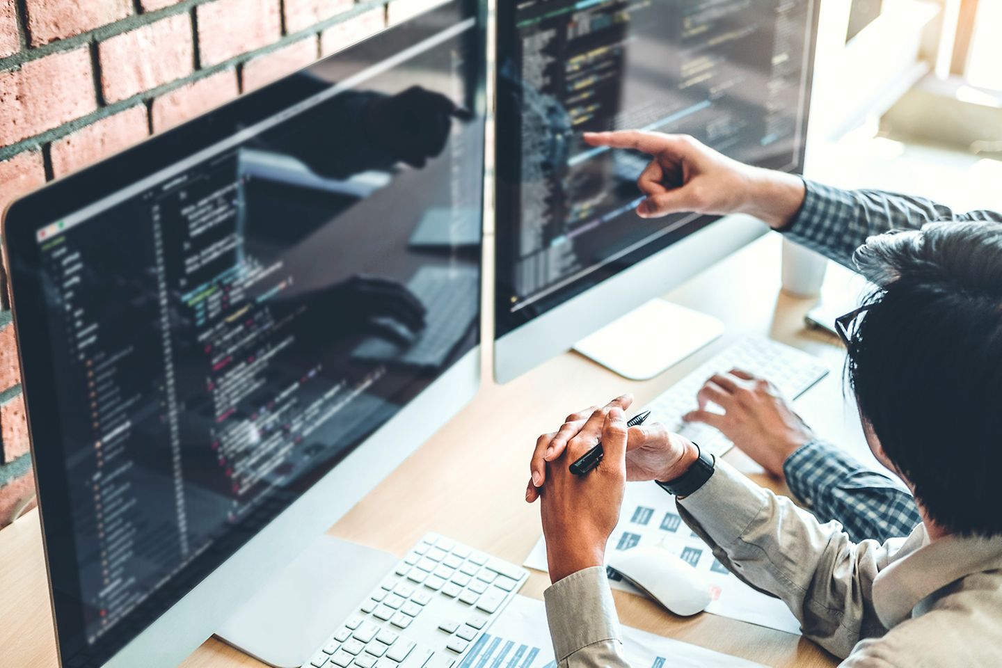 Visão de cima de dois homens diante da tela de um computador