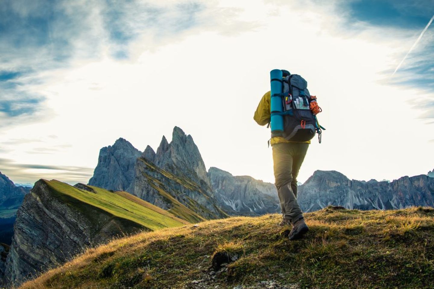 Homem jovem caminhando no pico das montanhas ao nascer do sol.