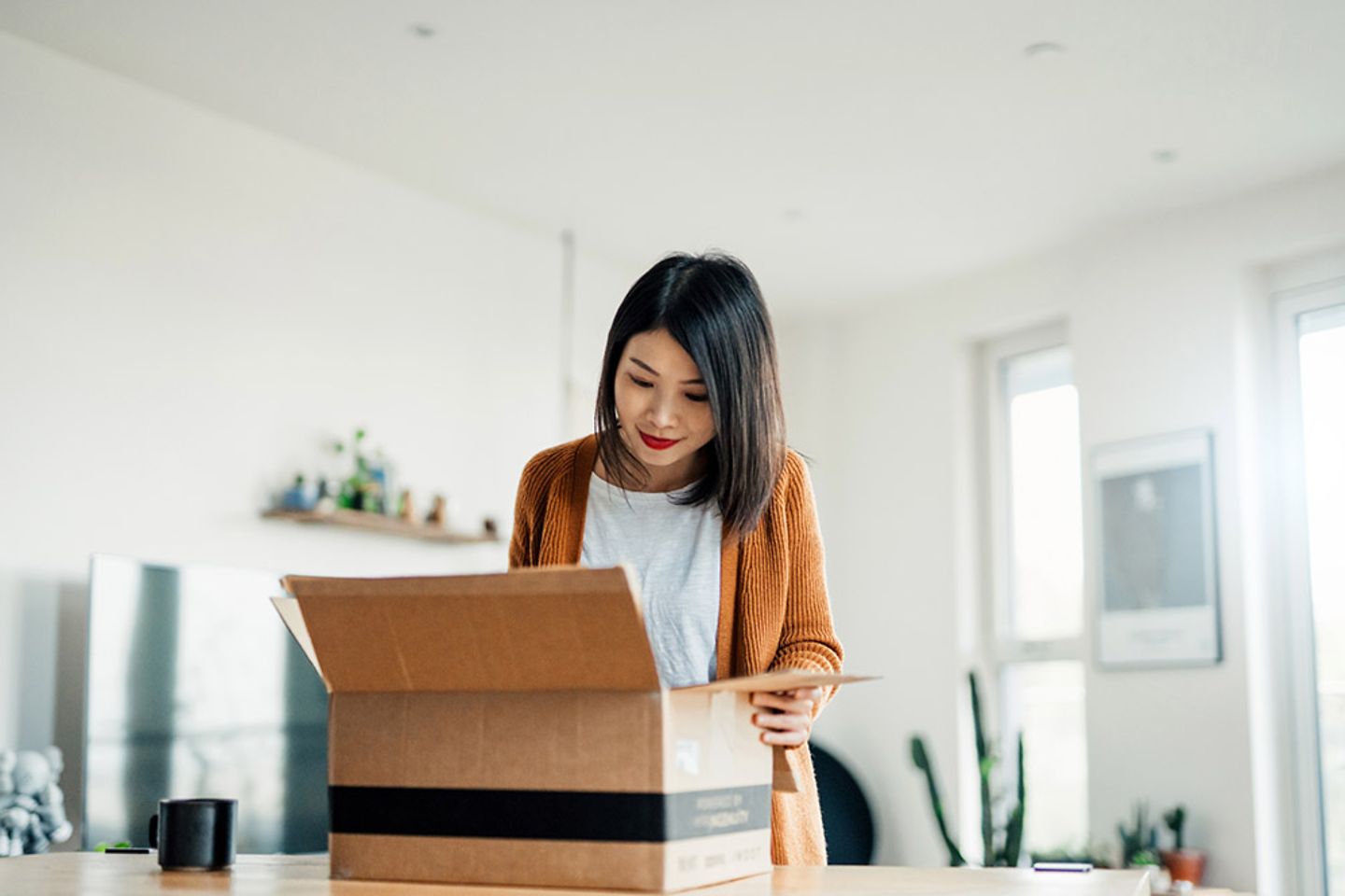 Eine Frau im Wohnzimmer, die ein Paket auspackt