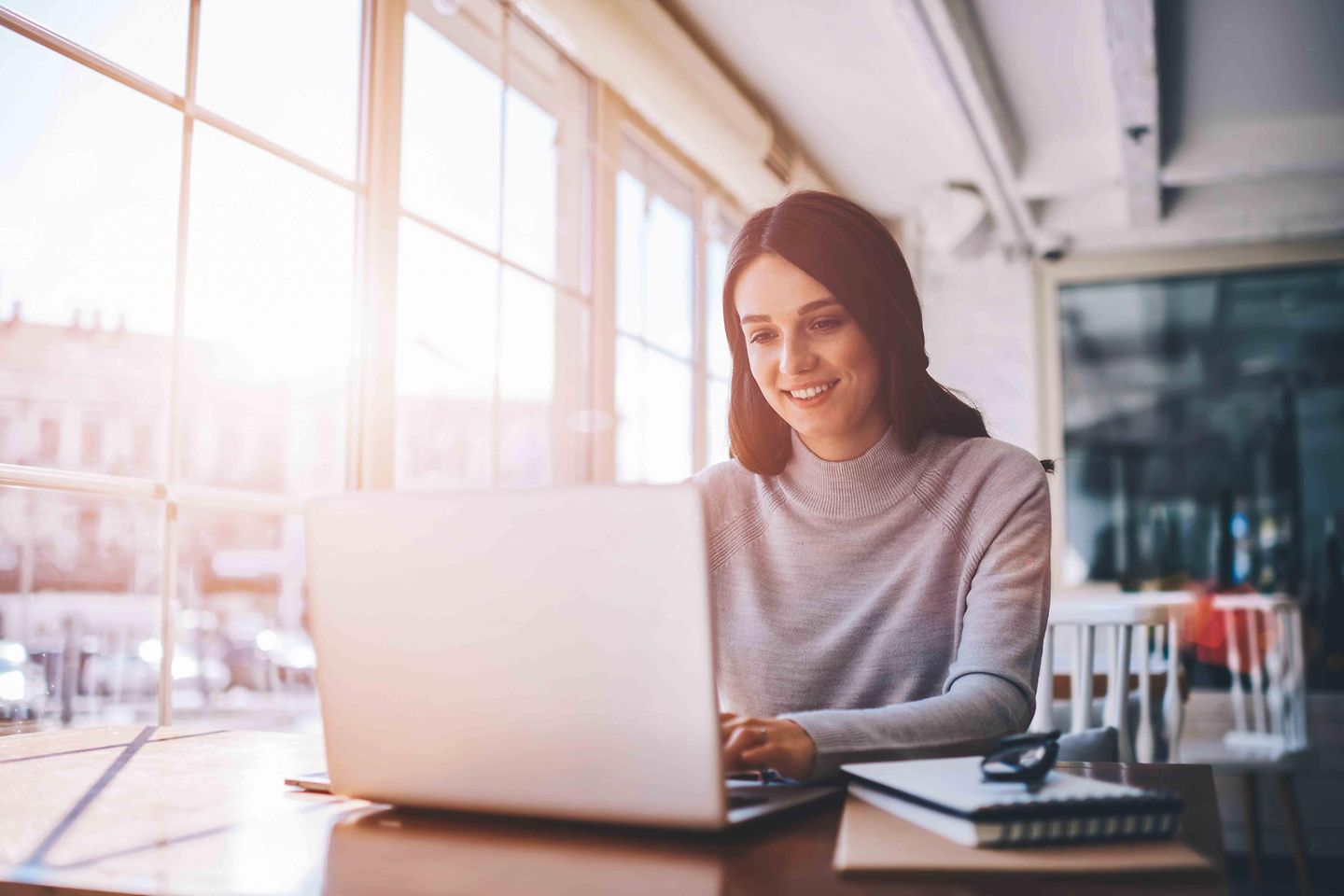 Junge Frau sitzt am Laptop und arbeitet