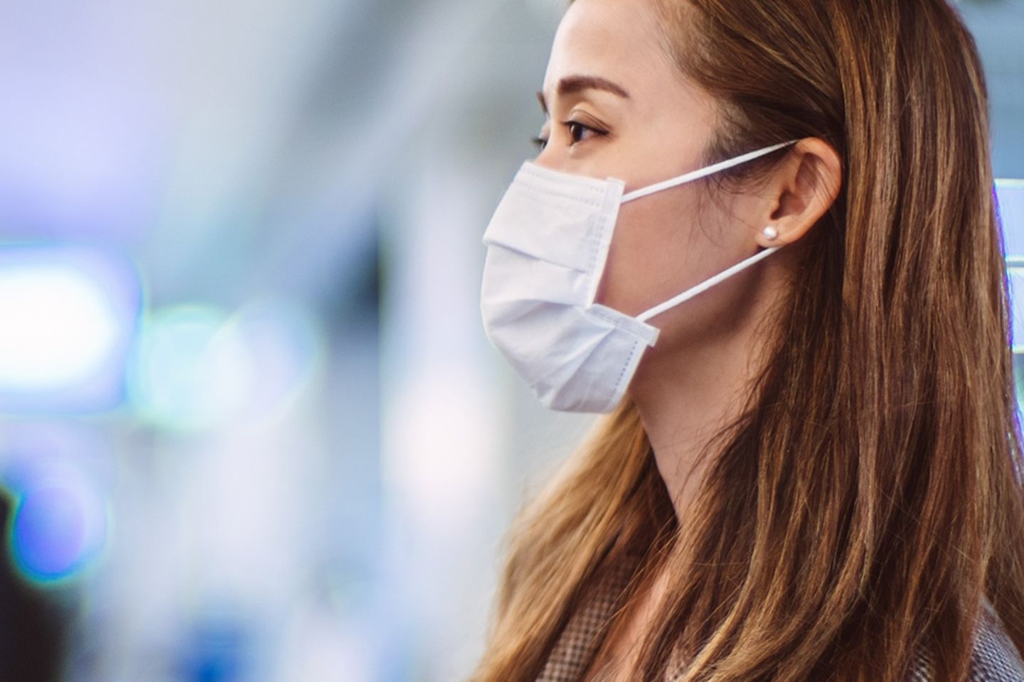  A woman wearing a face mask standing at a train station.