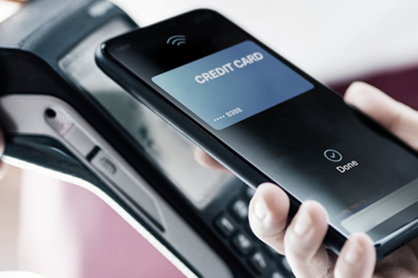 Smartphone wird an EC-Kartenlesegeraet gehalten. Kontaktloser Bezahlvorgang. 