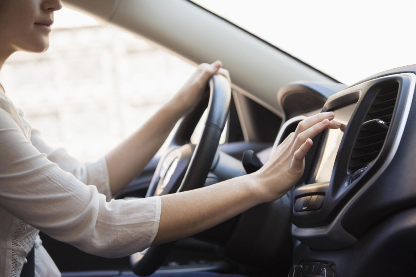 Frau sitzt im Connected Car und nimmt Änderungen am Touch-Display vor 