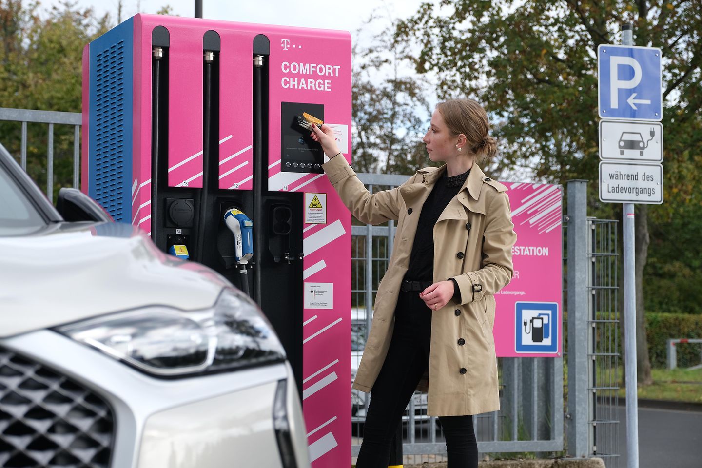 A woman holds a card in front of a charging station
