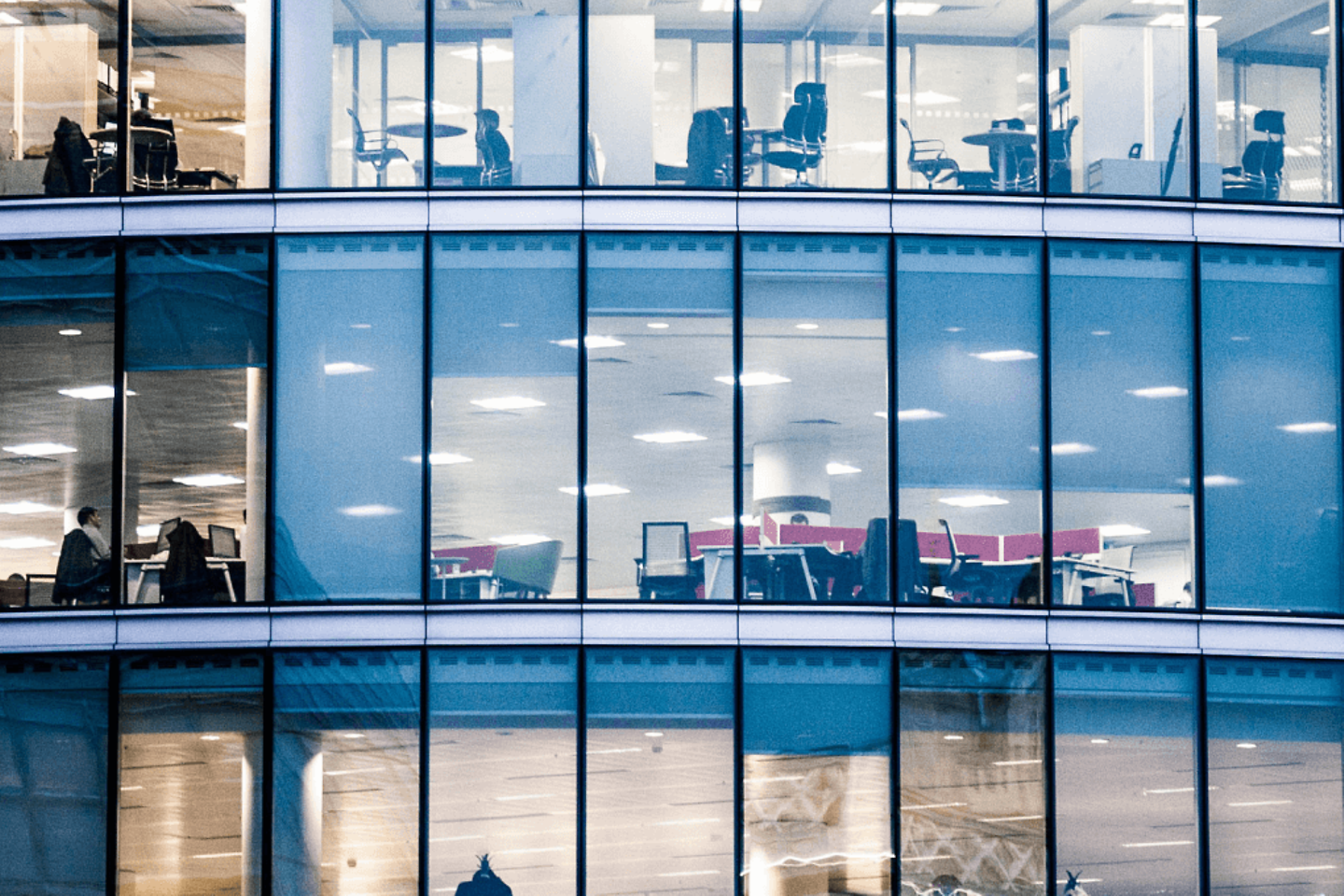 Immeuble de bureaux sur plusieurs étages éclairé de nuit.