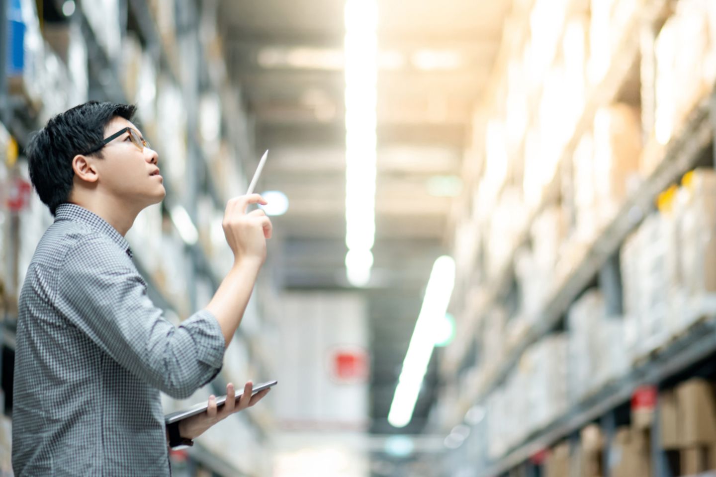 Man with a tablet and pen. Shelves in the background.