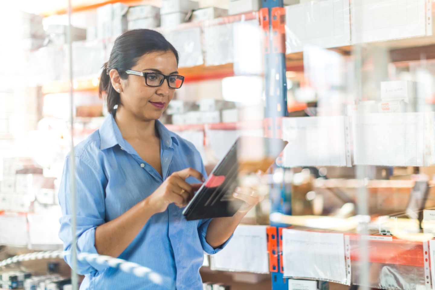 Woman looking at a tablet/tracker. Shelves in the background.