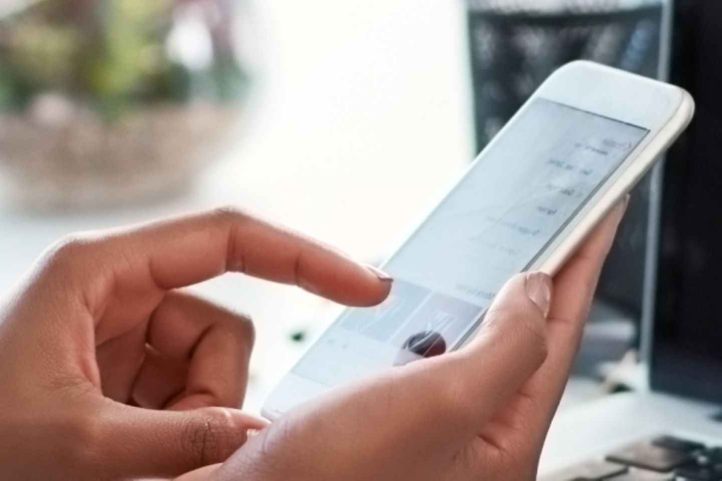 Hand with smartphone and laptop with graphs