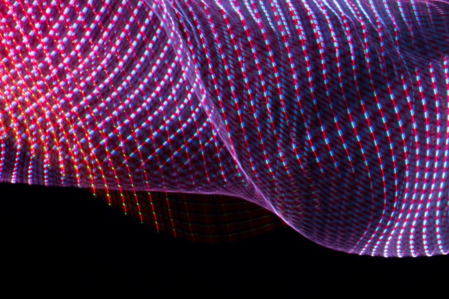 Fließendes Netz aus Licht in Magenta, Lila, Blau auf schwarzem Hintergrund.