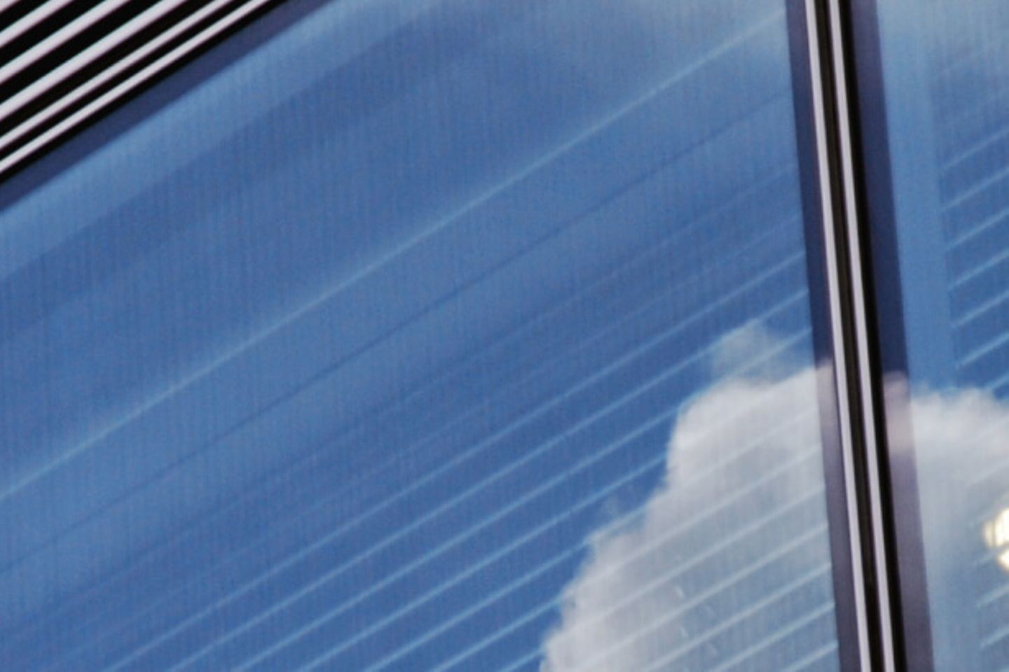 Wolken spiegeln sich in einem Gebäudefenster 