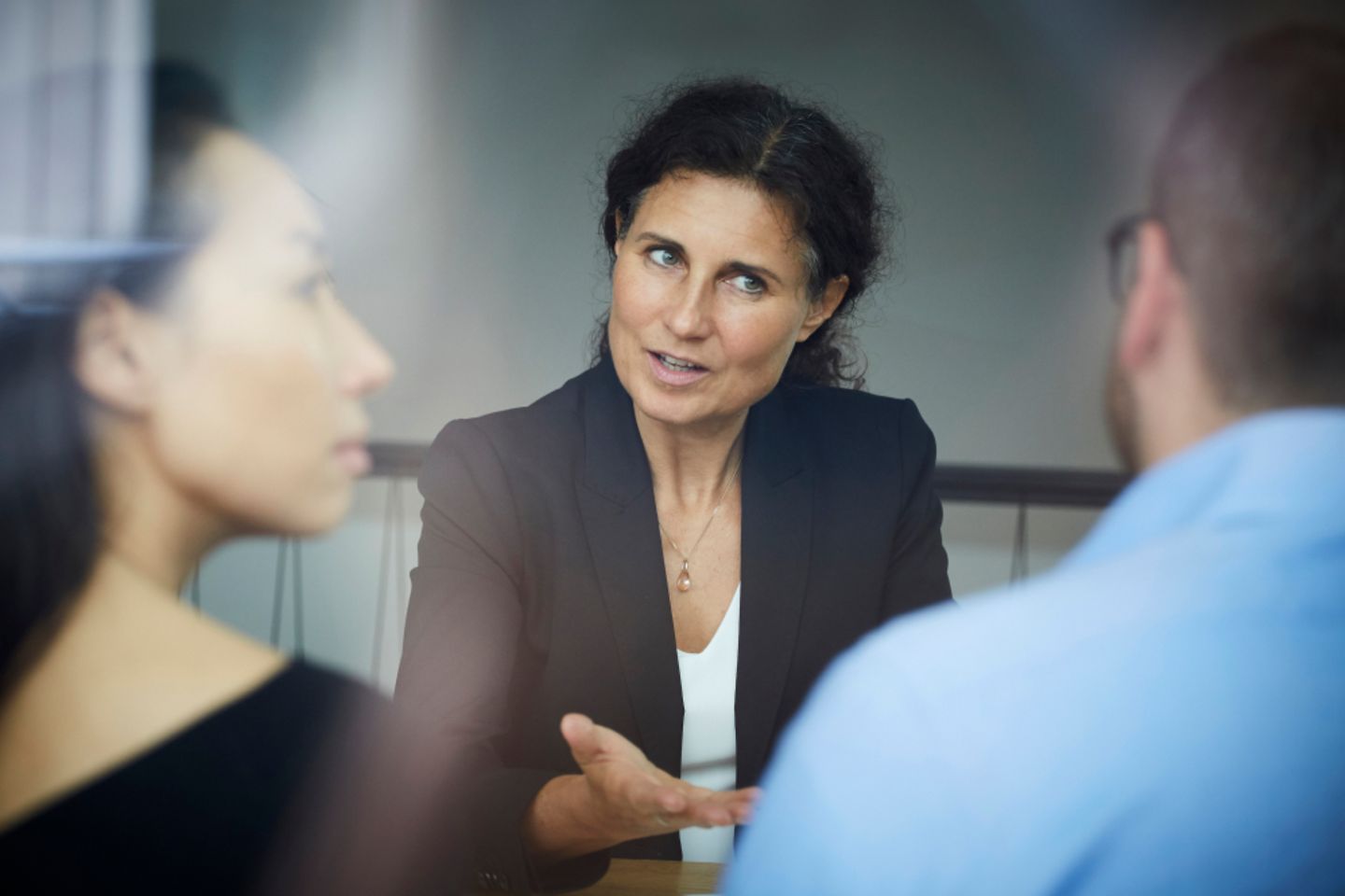 Uma empresária está conversando com um homem e uma mulher em uma reunião no escritório.